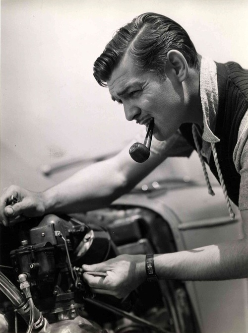 Clark Gable smoking a pipe and tinkering with a car | MATTHEW'S ISLAND